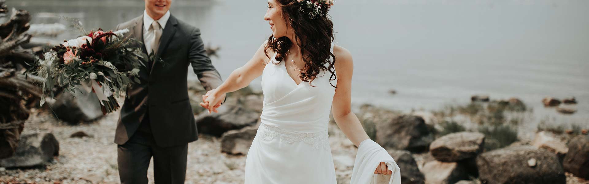 Hochzeitspaar entlang des Strandes laufend. Braut zieht Bräutigam hinter sich her